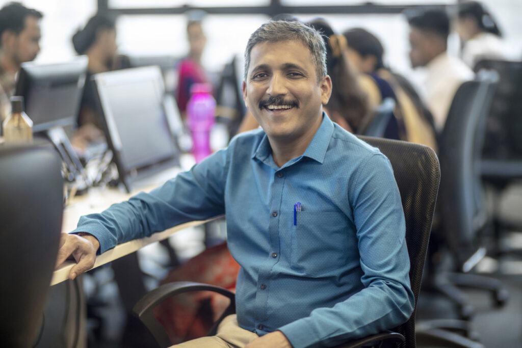 Smiling mature manager sitting at creative office